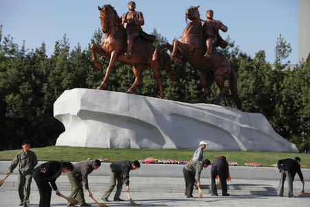 People sweep in front of statues of former North Korean leaders Kim Il Sung and Kim Jong Il in central Pyongyang, North Korea April 12, 2017. REUTERS/Damir Sagolj