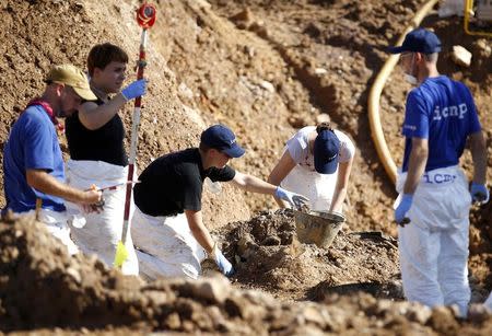 Forensic experts, members of the International Commision of Missing Persons (ICMP) and Bosnian workers search for human remains at a mass grave in the village of Tomasica near Prijedor in this October 22, 2013 file photo. REUTERS/Dado Ruvic