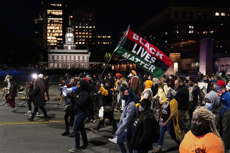 FILE - In this Nov. 4, 2020, file photo, demonstrators, including one carrying a Black Lives Matter flag, march past Independence Hall to urge that all votes be counted in Philadelphia, following the election. The Black Lives Matter Global Network Foundation, which grew out of the creation of the Black Lives Matter movement, is formally expanding a $3 million financial relief fund that it quietly launched in February 2021, to help people struggling to make ends meet during the ongoing coronavirus pandemic. (AP Photo/Matt Slocum, File)