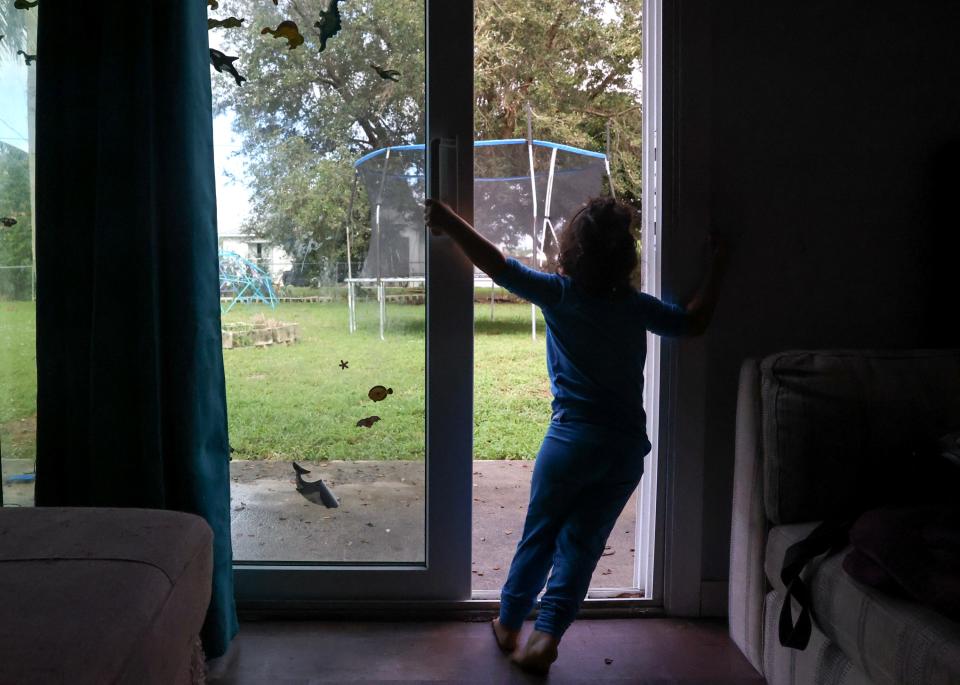 Josie Cherry, 2, closes the sliding glass door at her grandparents' home in Port St. Lucie, Fla., on Sunday, Dec. 17, 2023.