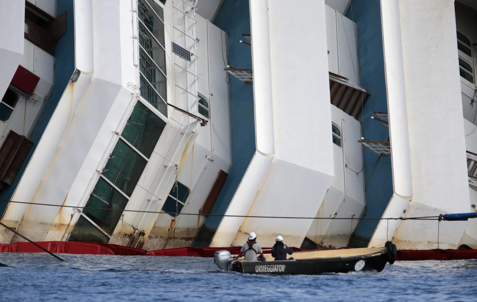 Salvage crew workers follow an operation to raise the capsized cruise liner Costa Concordia from a boat next to it, outside Giglio harbour September 16, 2013. Engineering teams began lifting the wrecked Costa Concordia liner upright on Monday, the start of one of the most complex and costly maritime salvage operations ever attempted. The so-called "parbuckling" operation will see the ship rotated by a series of cranes and hydraulic machines, pulling the hulk from above and below and slowly twisting it upright. REUTERS/Tony Gentile (ITALY - Tags: DISASTER SOCIETY MARITIME)