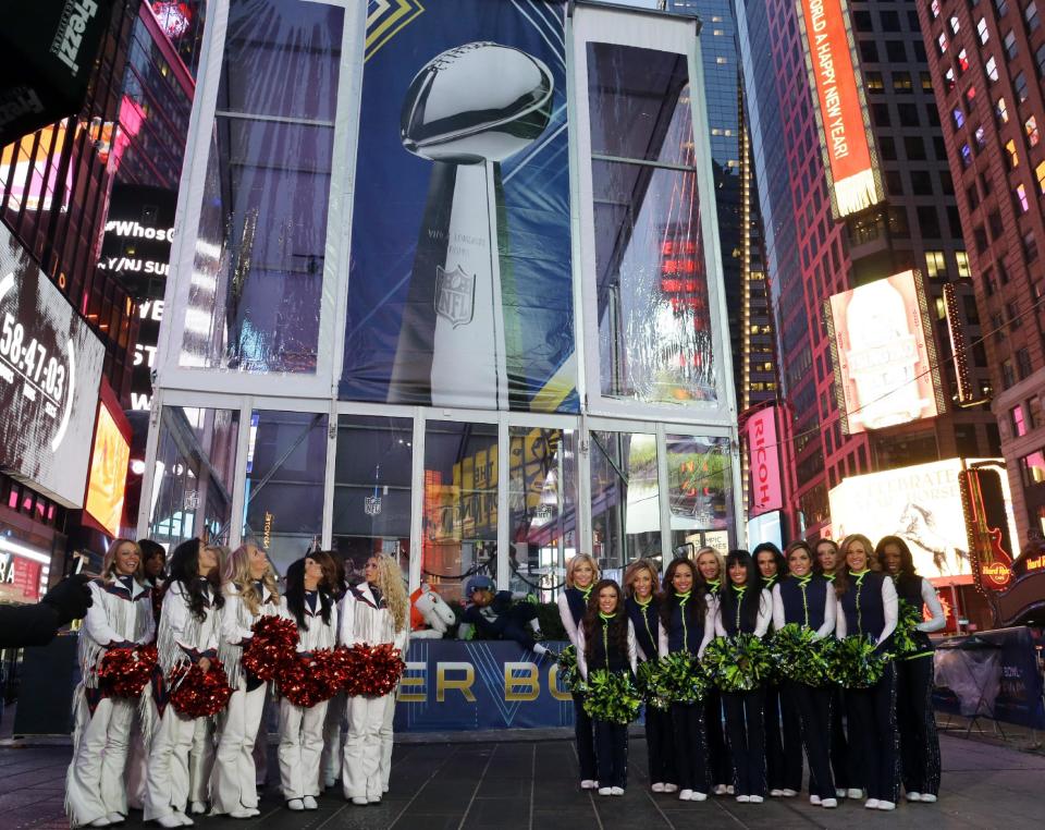 Denver Broncos cheerleaders and Seattle Seahawks Sea Gals cheerleaders stand in front of a photo of the Vince Lombardi Trophy, Friday, Jan. 31, 2014 during a live broadcast of Good Morning America at Times Square in New York. The Seattle Seahawks will play the Broncos Sunday in the NFL Super Bowl XLVIII football game in East Rutherford, N.J. (AP Photo/Ted S. Warren)