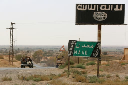 A vehicle drives past a billboard bearing the logo of the Islamic State group in Syria's Deir Ezzor province on September 24, 2017