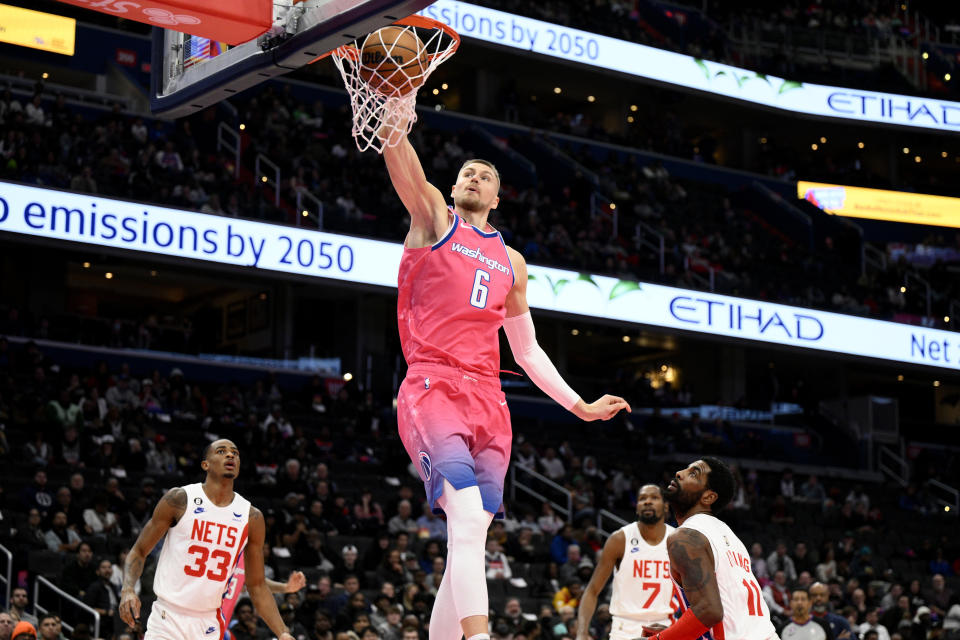 Washington Wizards center Kristaps Porzingis (6) dunks over Brooklyn Nets guard Kyrie Irving (11), center Nic Claxton (33) and forward Kevin Durant (7) during the first half of an NBA basketball game, Monday, Dec. 12, 2022, in Washington. (AP Photo/Nick Wass)