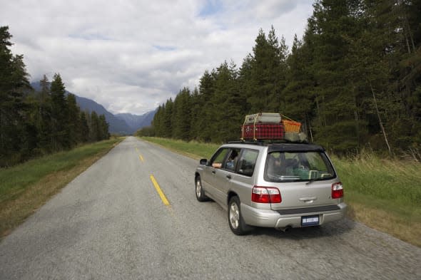 Sports utility vehicle driving on rural road, rear view