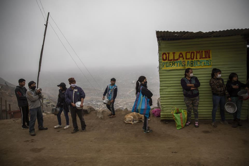 Residents wait in line at a "community pot," in the Nueva Esperanza neighborhood of Lima, Peru, Wednesday June 17, 2020. For many residents the "community pot" is their only defense against a hunger that's become a constant feature of life amid the new coronavirus pandemic. (AP Photo/Rodrigo Abd)