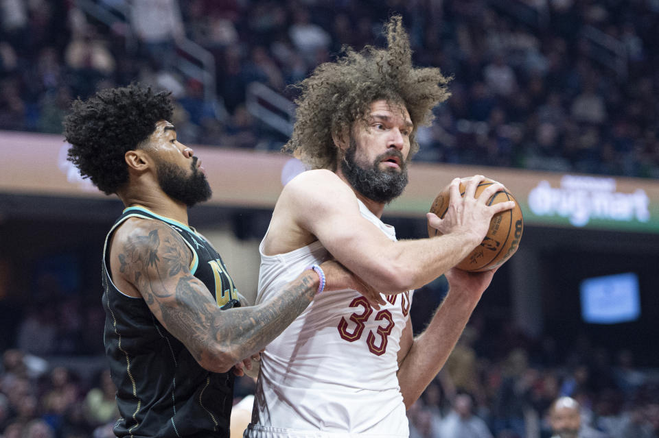 Cleveland Cavaliers' Robin Lopez (33) is defended by Charlotte Hornets' Nick Richards (4) during the first half of an NBA basketball game in Cleveland, Sunday, April 9, 2023. (AP Photo/Phil Long)