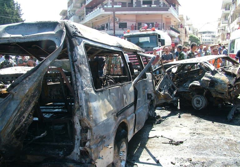 Picture released by the official Syrian Arab News Agency (SANA) on September 2, 2015 shows people looking at the wreckage of vehicles at the site of a reported car bombing in the government-controlled coastal city of Latakia