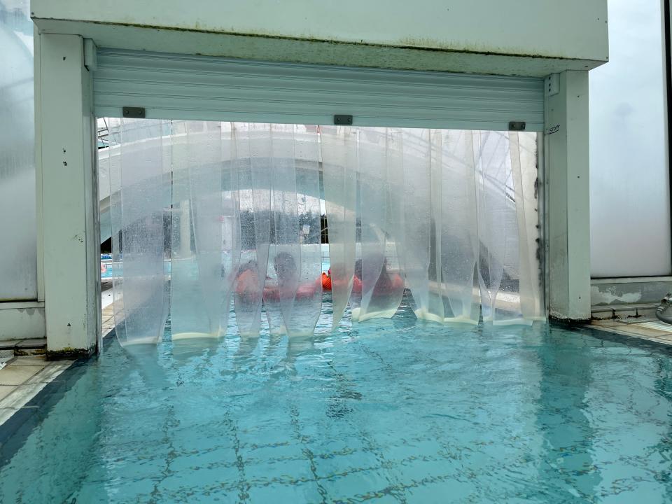 An pool with a plastic curtain leading to an outside section.