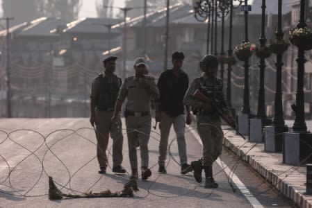 Indian security personnel patrol on deserted road during restrictions in Srinagar