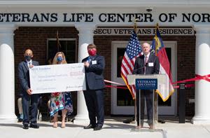 L to R: Retired Brigadier General Thomas Gorry-VLC Executive Director, Jama Campbell-SECU Foundation Executive Director, and John Turner-VLC Founder & Senior Advisor holding ceremonial check during presentation by Mike Lord, SECU President & CEO.