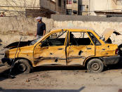 An Iraqi taxi driver inspects his damasged car after a car bomb attack near the Technology University in Sinaa Street in downtown Baghdad, Iraq, Wednesday, Jan. 15, 2014. A wave of bombings across Iraq striking busy markets and a funeral north of Baghdad killed tens of people Wednesday, authorities said, as the country remains gripped by violence after al-Qaida-linked militants took control of two cities in western Anbar province. (AP Photo/Karim Kadim)