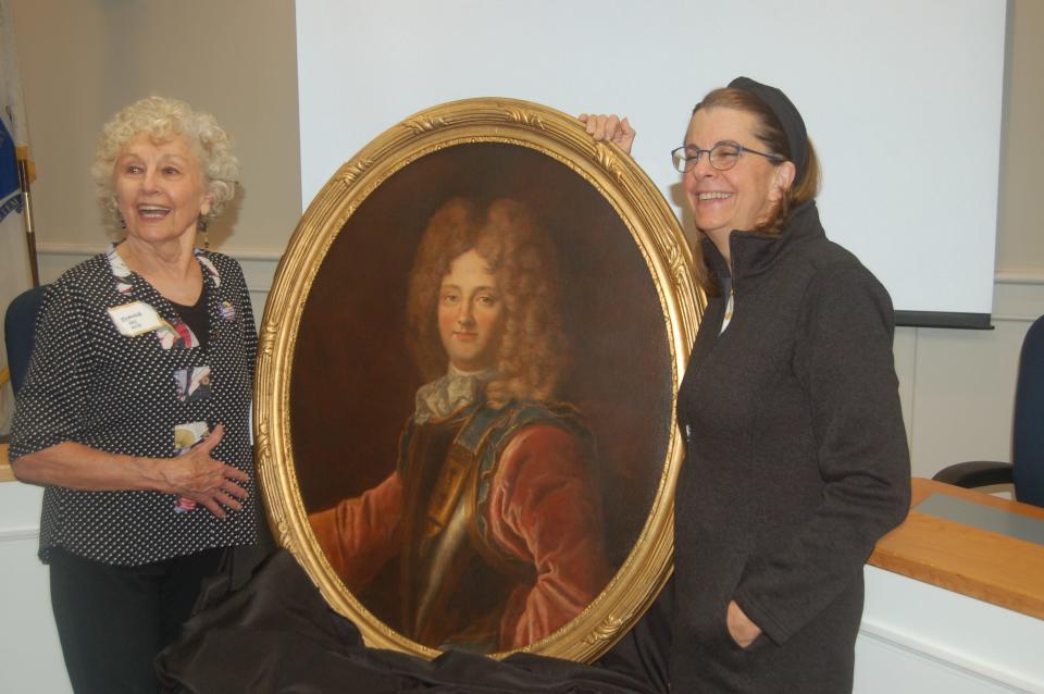 Johanna Keeley, left,  former chair of the Cultural Council, and Debra Dickinson, right, who restored the painting, flank the portrait of the Duke of Orleans.