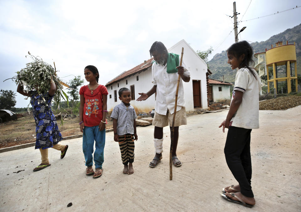 Kalmane Kamegowda, a 72-year-old shepherd, second from right, spends time with his grandchildren outside his home after visiting the hillock where he has created 16 ponds, in Dasanadoddi village, 120 kilometers (75 miles) west of Bengaluru, India, Wednesday, Nov. 25, 2020. Kamegowda, who never attended school, says he's spent at least $14,000 from his and his son’s earnings, mainly through selling sheep he tended over the years, to dig a chain of 16 ponds on a picturesque hill near his village. (AP Photo/Aijaz Rahi)