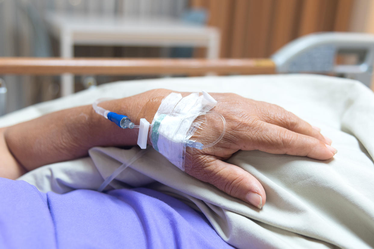 A patient's hands with an IV drip injection visible.