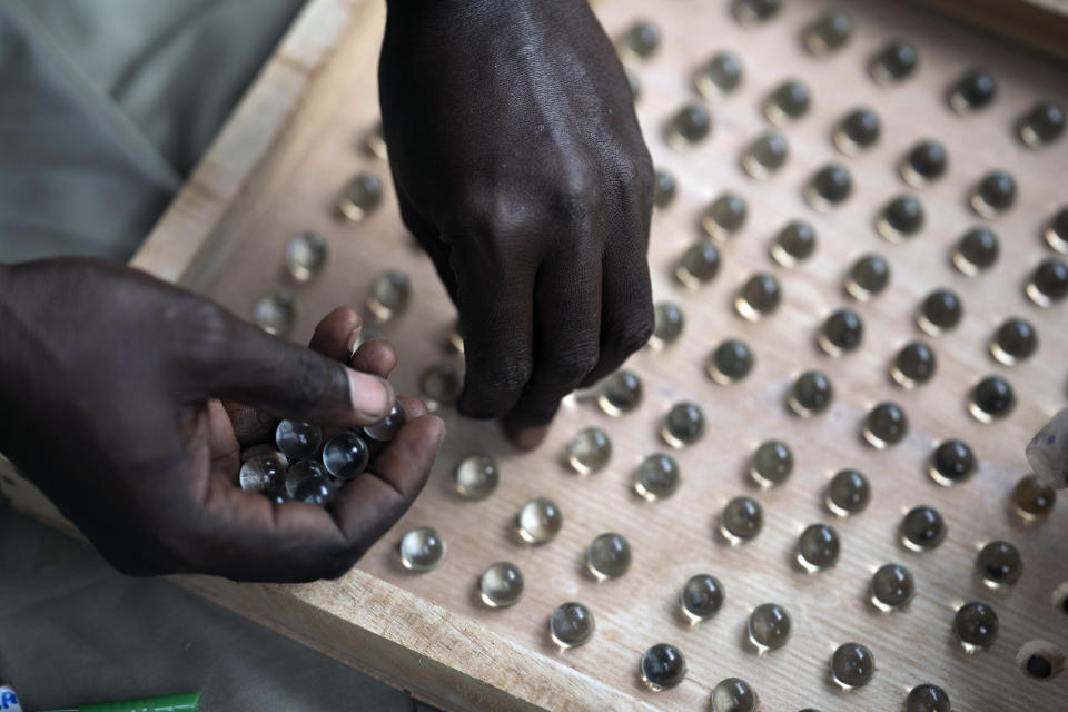 An electoral worker uses a counting board to tally marbles from a polling station during Gambia's presidential elections in Serrekunda, Gambia, Saturday, Dec. 4, 2021. Gambians vote in a historic election, one that for the first time will not have former dictator Yahya Jammeh appearing on the ballot. (AP Photo/Leo Correa)