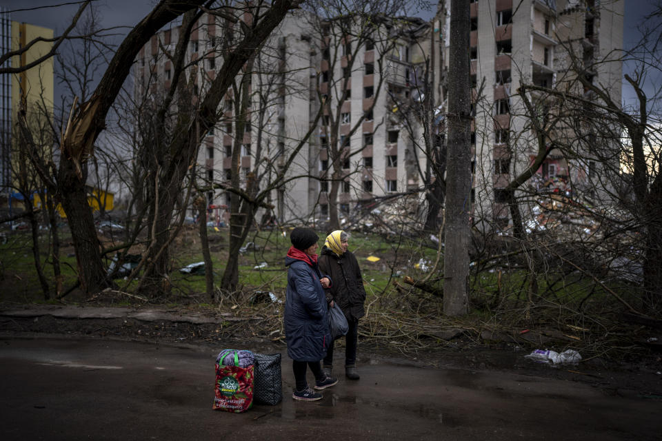 Women next to their belongings wait for transportation next to buildings destroyed by artillery in Chernihiv on Thursday, April 21, 2022. (AP Photo/Emilio Morenatti)