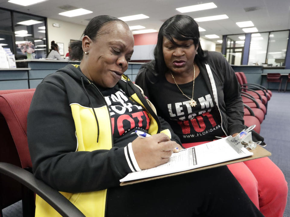 Former felon Yolanda Wilcox, left, fills out a voter registration form as her best friend Gale Buswell looks on at the Supervisor of Elections office Tuesday, Jan. 8, 2019, in Orlando, Fla. Former felons in Florida began registering for elections on Tuesday, when an amendment that restores their voting rights went into effect. (AP Photo/John Raoux)