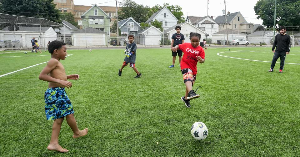 A group of children pass a soccer ball Friday on the newly installed turf fields at Burnham Park in Milwaukee.
