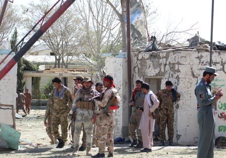 Afghan security forces stand at the site of a car bomb attack in Qalat, capital of Zabul province