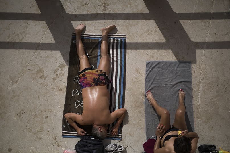 Personas tomando el sol en la playa.