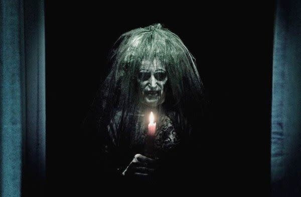 an old woman ghost stands in a dark room in a scene from 'insidious'