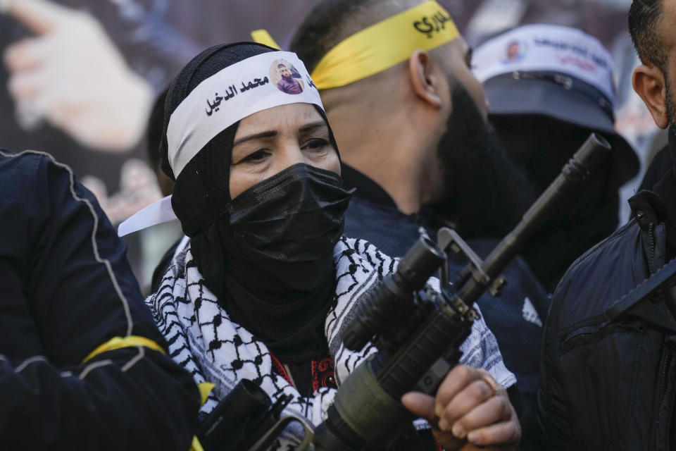 A masked Palestinian woman holds a gun as Palestinian gunmen gather in solidarity with Palestinians that where killed in clashes with Israeli troops, in the West Bank city of Nablus, Friday, Feb. 10, 2023. (AP Photo/Majdi Mohammed)