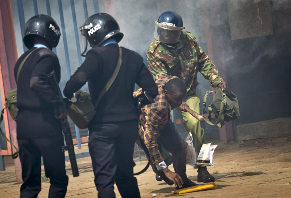 An opposition supporter is beaten with a wooden club by riot police as he tries to flee during a protest in downtown Nairobi, Kenya, May 16, 2016. Kenyan police have tear-gassed and beaten opposition supporters during a protest demanding the disbandment of the electoral authority over alleged bias and corruption. (AP Photo/Ben Curtis)