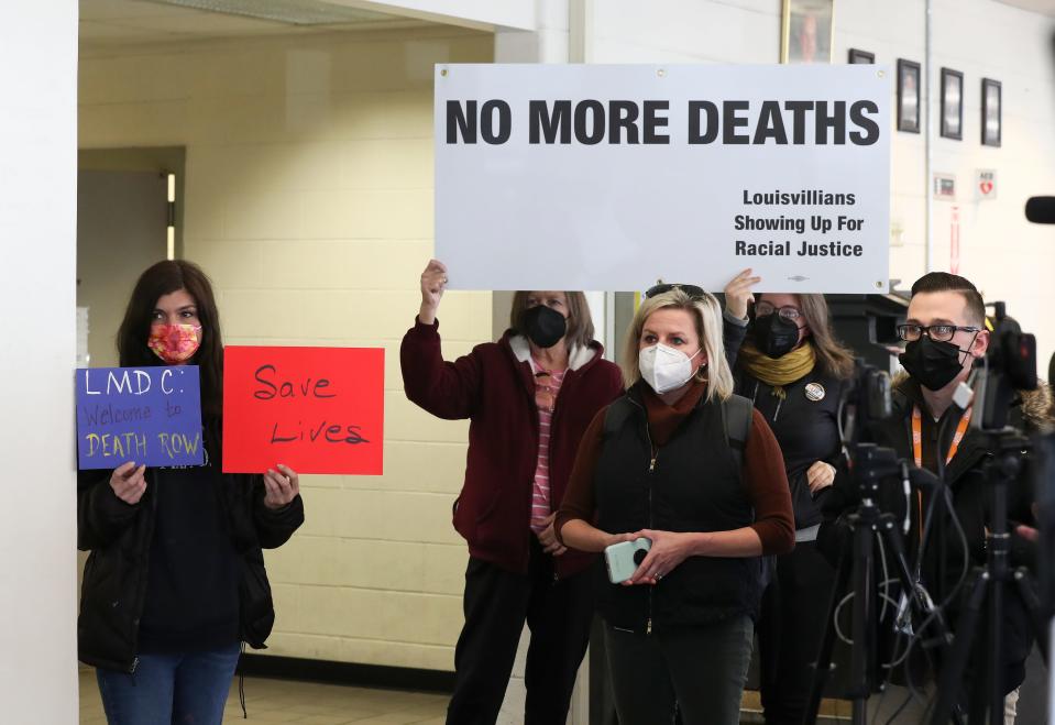 Protesters held signs in the background of a press conference where Mayor Greg Fischer and Metro Corrections Director Dwayne Clark spoke to the media about the most recent inmate death at Metro Corrections on Feb. 6, 2022.  They said an investigation has begun.