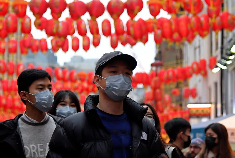 People wear masks as they walk in Chinatown district, in London