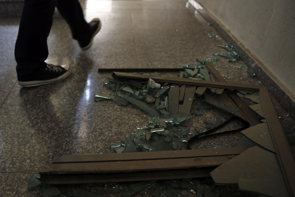 A man passes broken glass inside the building that houses Hezbollah's media office in a stronghold of the Lebanese Hezbollah group in a southern suburb of Beirut, Lebanon, Sunday, Aug. 25, 2019. Two Israeli drones crashed in a Hezbollah stronghold in the Lebanese capital overnight without the militants firing on them, a spokesman for the group said Sunday, saying the first fell on the roof of a building housing Hezbollah's media office while the second landed in a plot behind it. (AP Photo/Bilal Hussein)