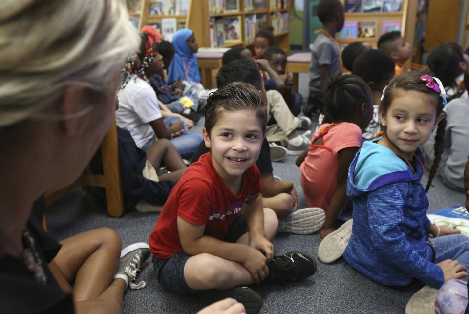 Students Anthony Gonzalez, middle, and Kritza Ardon Blanco, right, list to teacher Kristine Jones, left, in the library at Valencia Newcomer School Thursday, Oct. 17, 2019, in Phoenix. Children from around the world are learning the English skills and American classroom customs they need to succeed at so-called newcomer schools. Valencia Newcomer School in Phoenix is among a handful of such public schools in the United States dedicated exclusively to helping some of the thousands of children who arrive in the country annually. (AP Photo/Ross D. Franklin)