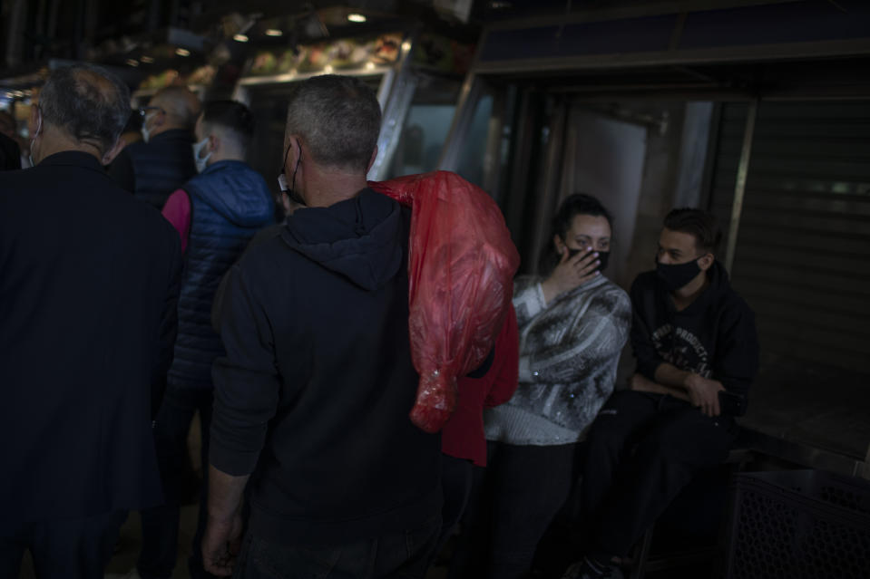 A consumer wearing protective face mask carries a lamb at the main meat market of Athens during Orthodox Holy Week, Thursday, April 29, 2021. (AP Photo/Petros Giannakouris)