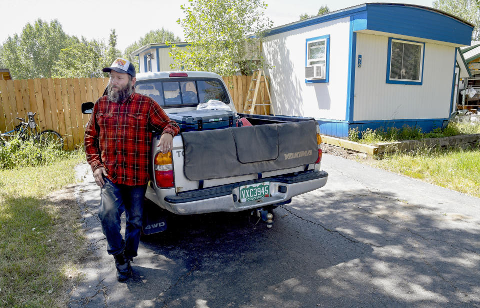 Sean Bailey stands outside the mobile home where he rents a room, Thursday, Aug. 4, 2022, in Steamboat Springs, Colo. Bailey, who moved to Steamboat Springs in 2019, has been on a waitlist for three years to get one of Steamboat's affordable housing apartments. (AP Photo/Thomas Peipert)