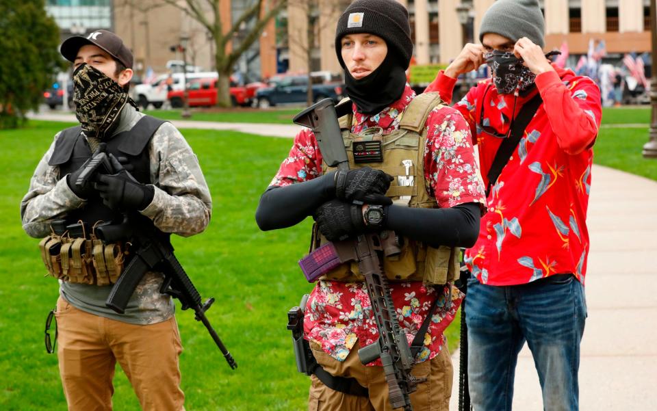  In this file photo taken on April 30, 2020 Armed protesters provide security as demonstrators take part in an "American Patriot Rally," organized by Michigan United for Liberty on the steps of the Michigan State Capitol in Lansing, demanding the reopening of businesses. - Jef Kowalsky/AFP/Getty