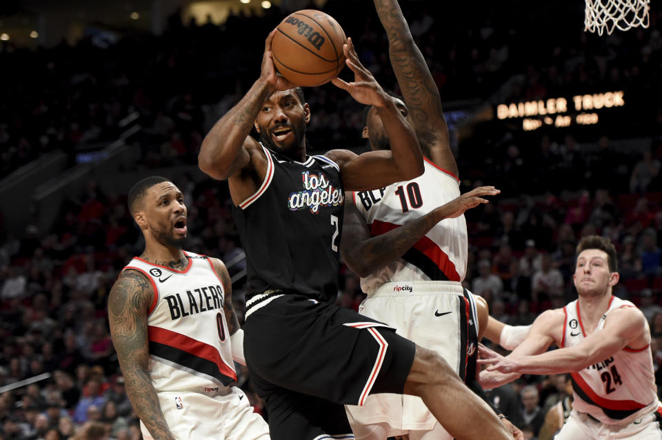 Los Angeles Clippers forward Kawhi Leonard, center, drives to the basket against Portland Trail Blazers forward Nassir Little, right, and guard Damian Lillard, left, during the second half of an NBA basketball game in Portland, Ore., Sunday, March 19, 2023. The Clippers won 117-102. (AP Photo/Steve Dykes)