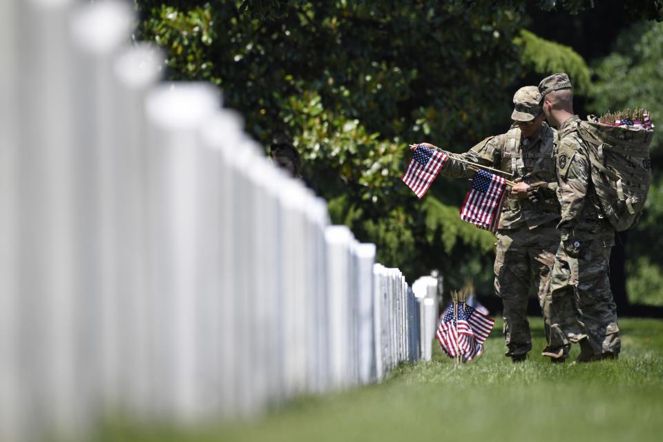 FILE -In this May 23, 2019 file photo, members of the 3rd U.S. Infantry Regiment, also known as The Old Guard, place flags in front of each headstone for "Flags-In" at Arlington National Cemetery in Arlington, Va. The Army is proposing new rules that would significantly restrict eligibility for burial at Arlington National Cemetery in an effort to preserve a dwindling number of gravesites well into the future. (AP Photo/Susan Walsh, File)