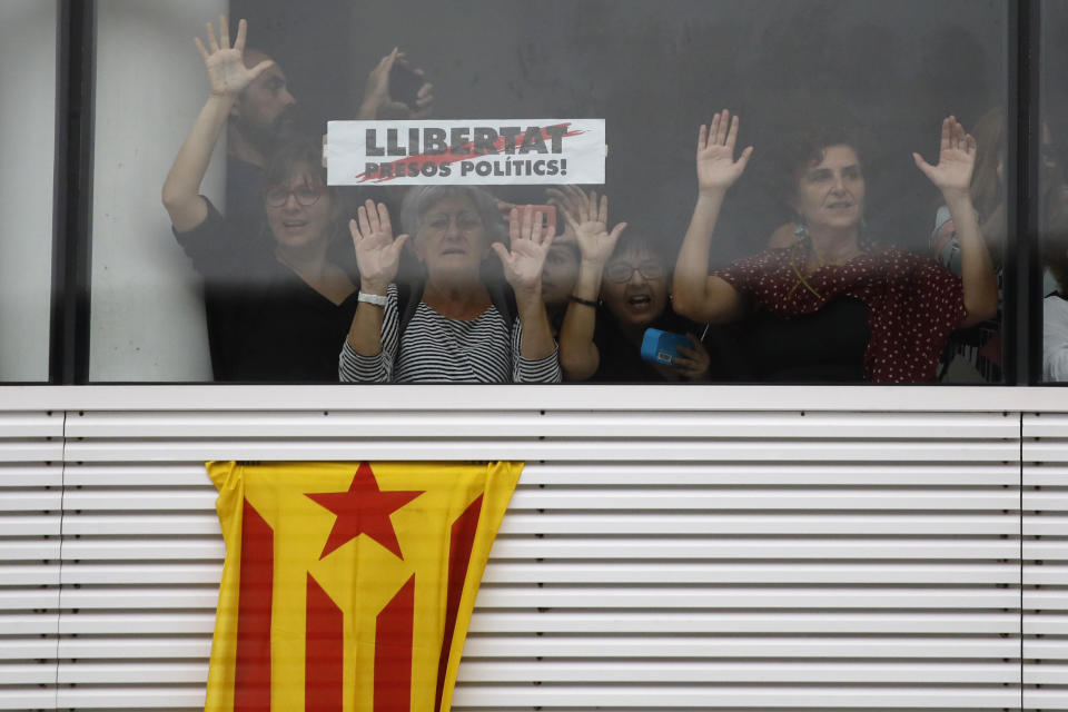 Protestors stand behind a banner reading in Catalan, "Freedom for Political Prisoners" at El Prat airport in Barcelona, Spain, Monday, Oct. 14, 2019. Spain's Supreme Court on Monday convicted 12 former Catalan politicians and activists for their roles in a secession bid in 2017, a ruling that immediately inflamed independence supporters in the wealthy northeastern region. (AP Photo/Emilio Morenatti)