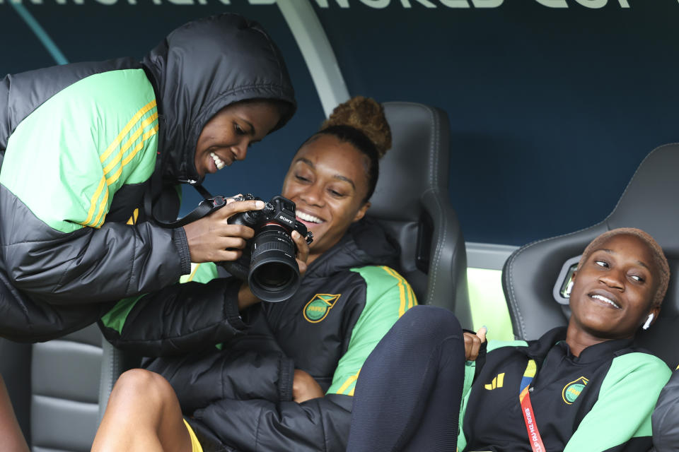 Jamaica's Khadija Shaw, left, shows a photo to teammate Chantelle Swaby during a familiarization visit to Melbourne Rectangular Stadium before a Women's World Cup Group F match against Brazil in Melbourne, Australia, Tuesday, Aug. 1, 2023. Two crowd funding project have raised more than US$98,000 to support the team through the tournament. (AP Photo/Victoria Adkins)