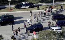 FILE - In this Feb. 14, 2018 file photo, students hold their hands in the air as they are evacuated by police from Marjory Stoneman Douglas High School in Parkland, Fla., after a shooter opened fire on the campus. The 12 jurors and 10 alternates chosen this past week to decide whether Cruz is executed will be exposed to horrific images and emotional testimony, but must deal with any mental anguish alone. (Mike Stocker/South Florida Sun-Sentinel via AP, FIle)