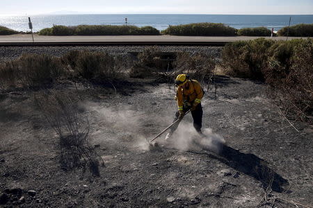 A firefighter mops up during a wildfire in the Solimar Beach area of Ventura County, California December 26, 2015. REUTERS/Patrick T. Fallon