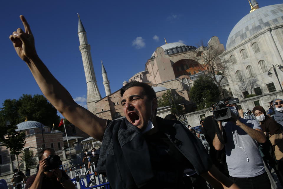 People chant slogans following Turkey's Council of State's decision, outside the Byzantine-era Hagia Sophia, one of Istanbul's main tourist attractions in the historic Sultanahmet district of Istanbul, Friday, July 10, 2020.Turkey's Council of State, threw its weight behind a petition brought by a religious group and annulled a 1934 cabinet decision that changed the 6th century building into a museum. The ruling allows the government to restore the Hagia Sophia's previous status as a mosque.The decision was in line with the Turkish President's Recep Tayyip Erdogan's calls to turn the hugely symbolic world heritage site into a mosque despite widespread international criticism, including from the United States and Orthodox Christian leaders. (AP Photo/Emrah Gurel)