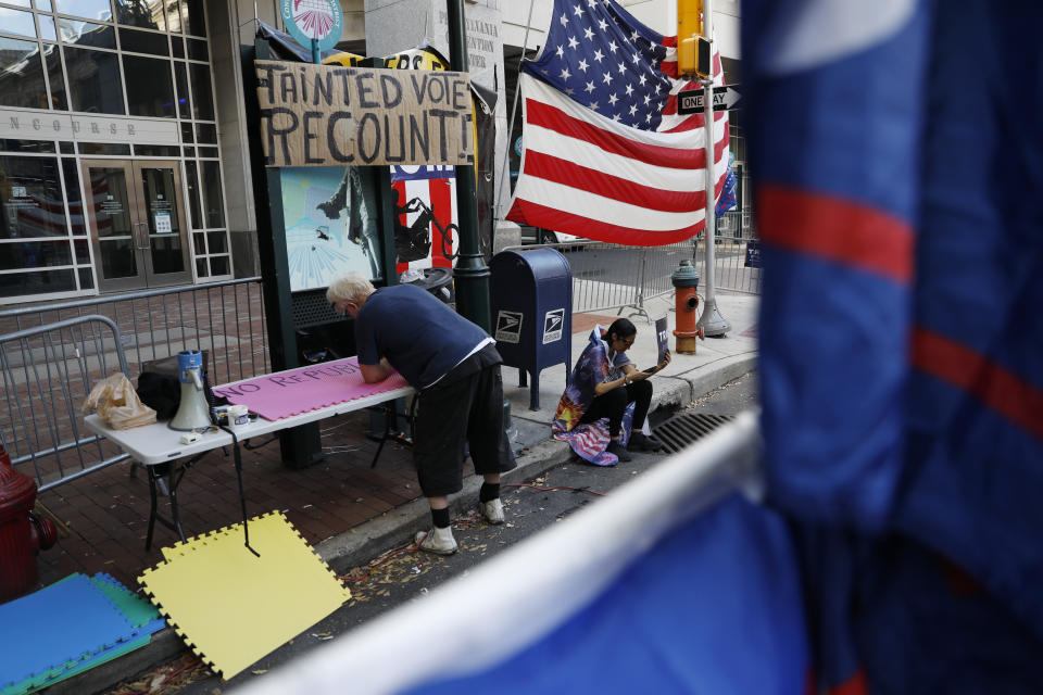 A man makes signs as a handful of supporters of President Donald Trump continue to protest outside the Pennsylvania Convention Center, in Philadelphia, Tuesday, Nov. 10, 2020. (AP Photo/Rebecca Blackwell)