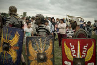 Men wearing Roman soldiers outfits walk past the public during the Romula Fest historic reenactment event in the village of Resca, Romania, Saturday, Sept. 3, 2022. Members of historic NGOs and volunteers gathered in a field outside a southern Romanian village, once part of the Romula Malva, Roman Empire era city, aiming to raise awareness for history through realistic reenactments of battles between Roman legions and local Dacian tribes.(AP Photo/Andreea Alexandru)