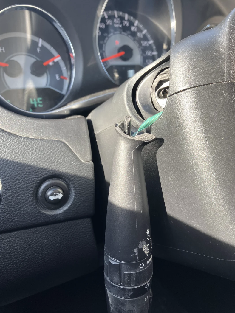 Close-up of a car's steering wheel with a dangling turn signal lever