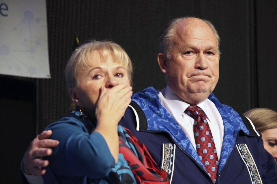 Alaska first lady Donna Walker, left, blows kisses to the crowd and Gov. Bill Walker reacts at the Alaska Federation of Natives conference Friday, Oct. 19, 2018, in Anchorage, Alaska, after announcing he was suspending his re-election bid. Walker's re-election plans were dealt a blow earlier in the week after his running mate, Lt. Gov. Byron Mallott, resigned after making an inappropriate overture toward a woman. (AP Photo/Mark Thiessen)