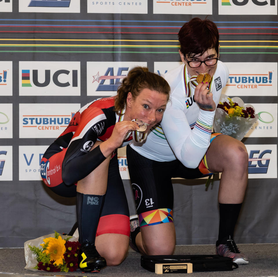 In this Oct. 13, 2018 photo provided by Craig Huffman, transgender cyclist Rachel McKinnon of Canada, right, bites her gold medal with silver medalist Carolien Van Herrikhuyzen of the Netherlands during the UCI Masters Track Cycling World Championships in Carson, Calif. Initially, McKinnon was elated with her win, even though one of her top rivals pulled out of the final at the last minute. But there quickly was a downside to the victory, as a photo gained attention across the internet showing her on the podium with the two smaller, skinnier runners-up. (Craig Huffman/Craig Huffman Photography via AP)