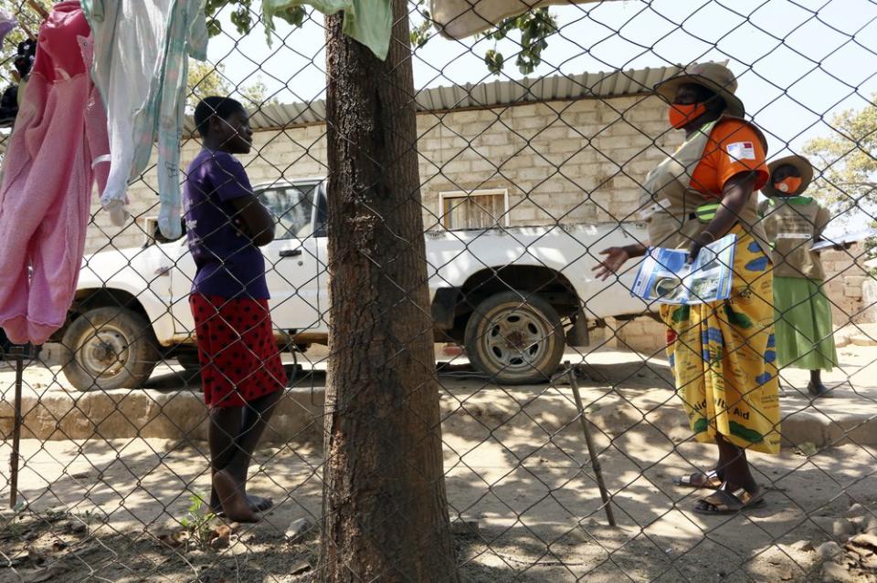 Community health worker, Rosemary Rambire, right, speaks to a young girl during a COVID-19 awareness campaign in Chitungwiza, on the outskirts of Harare, Zimbabwe, Wednesday, Sept. 23, 2020. (AP Photo/Tsvangirayi Mukwazhi)