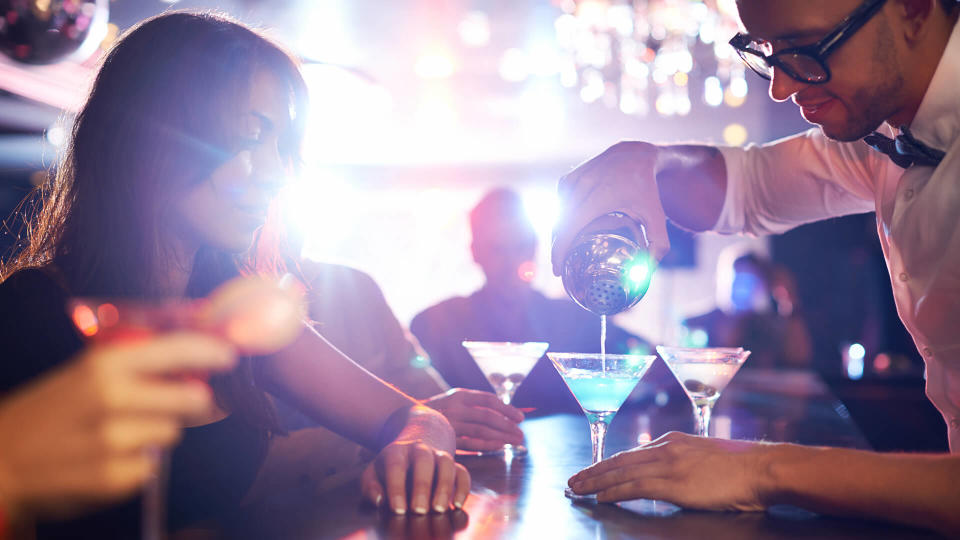 Barman pouring alcohol pouring cocktail for attractive girl.