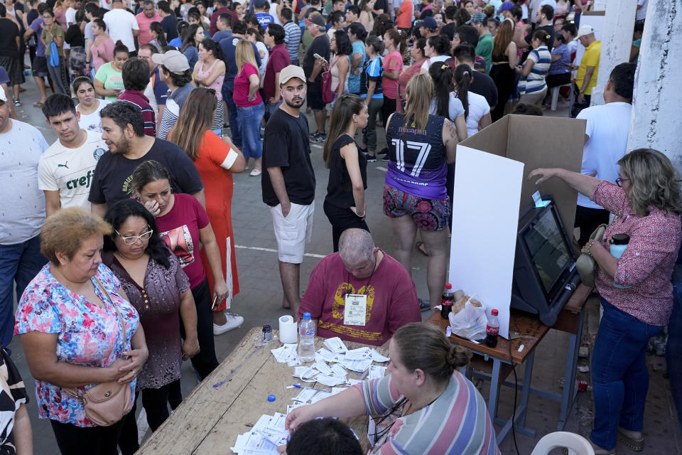 A woman votes, right, as others line up for their turn during general elections in Asuncion, Sunday, April 30, 2023. (AP Photo/Jorge Saenz)